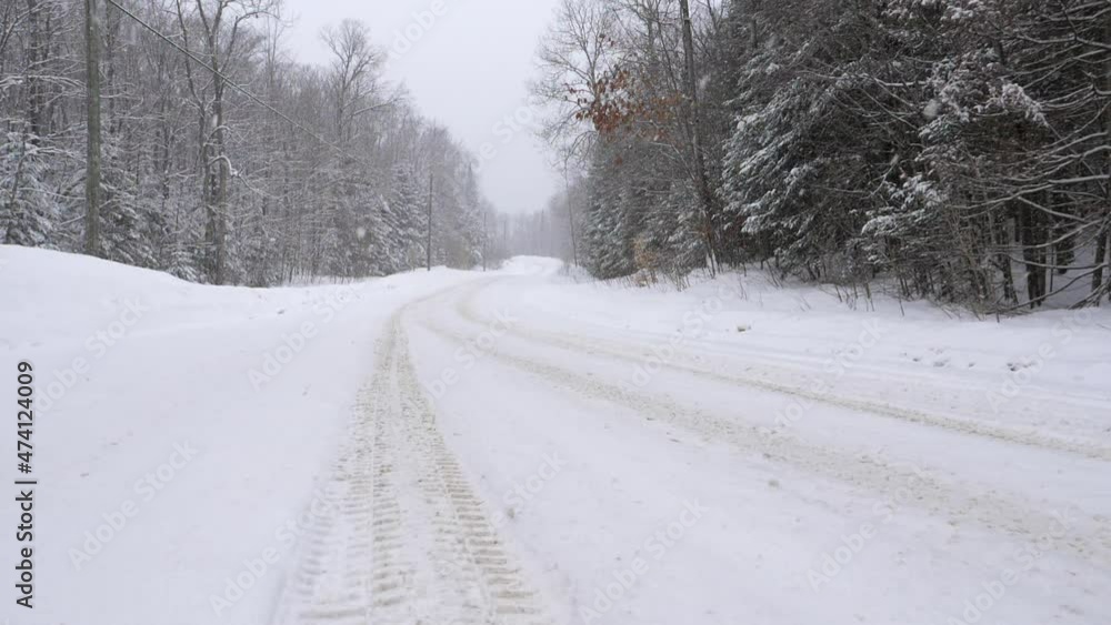 Tire tracks on curvy rural snow-covered winter road. Slow motion snow falling. Haliburton, Ontario, Canada. Tire tracks on curvy rural snow-covered winter road. Slow motion snow falling. Haliburton, Ontario, Canada.