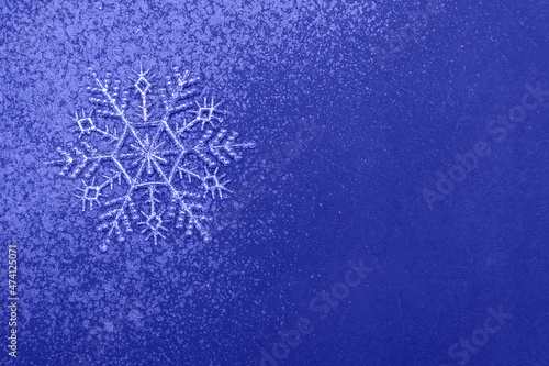 Minimalistic christmas background, silver snowflake and glitter on blue backdrop
