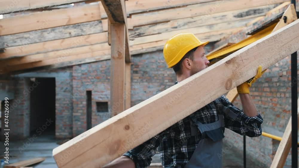 Walks with piece of board. Construction worker in uniform and safety equipment have job on building Walks with piece of board. Construction worker in uniform and safety equipment have job on building