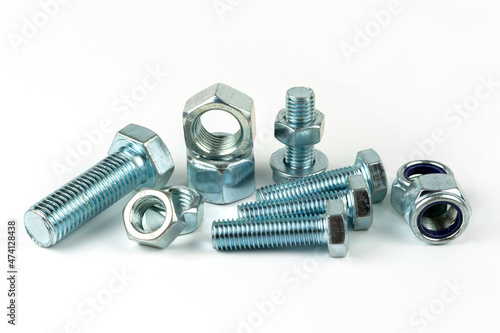 Large metal nuts with silver metal bolts. Close-up on a white background. A group of several nuts and bolts