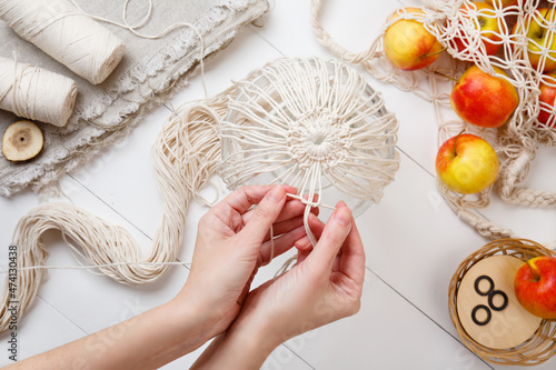 string bag weaving guide. Woman hands Making Eco bag for shopping in grocery store. DIY eco shopper. Fresh fruits. Eco-friendly concept. Reusable mesh shopper. Zero waste. Plastic-free concept