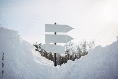 Empty white pointers, guidepost against winter nature background. Directional arrow signs on pole in snowy forest. Christmas and New Year concept.