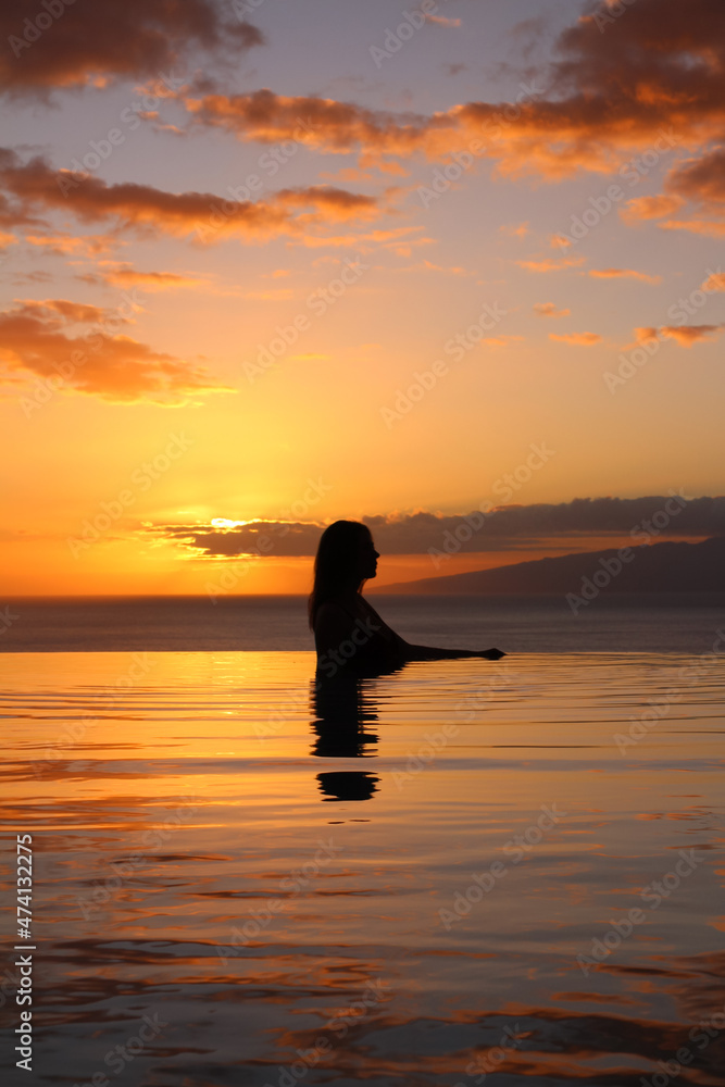 TENERIFE. SPAIN. a Girl in profile stands in the pool, against the background of a beautiful sunset and the ocean. hotel TENERIFE. SPAIN. a Girl in profile stands in the pool, against the background of a beautiful sunset and the ocean. hotel