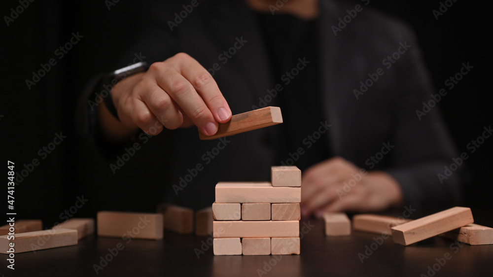 Businessman placing wooden block on a tower. Strategy and start up business concept. Businessman placing wooden block on a tower. Strategy and start up business concept.
