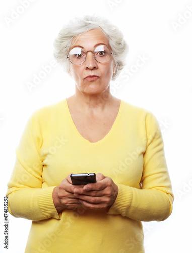 Pretty senior woman in casual outfit using modern smartphone