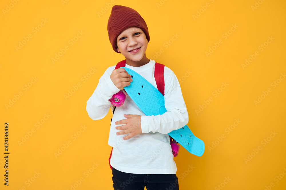 Cool smiling boy with red backpack blue skateboard studio lifestyle Cool smiling boy with red backpack blue skateboard studio lifestyle
