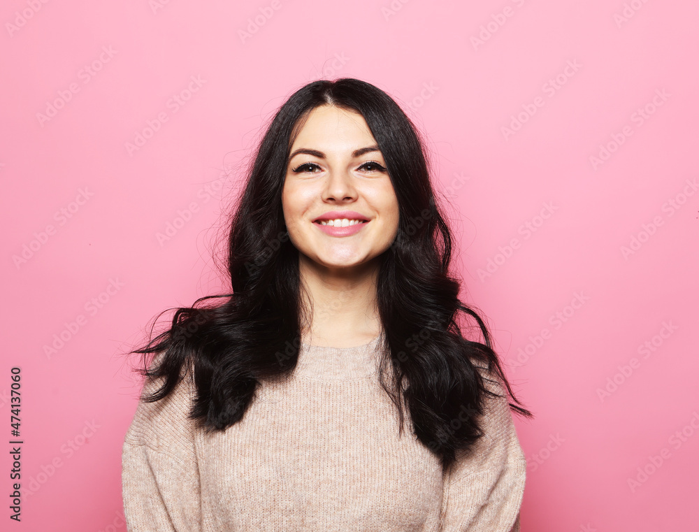 Young beautiful brunette woman with curly hair wearing casual pink sweater with a happy and cool smile on face. Young beautiful brunette woman with curly hair wearing casual pink sweater with a happy and cool smile on face.