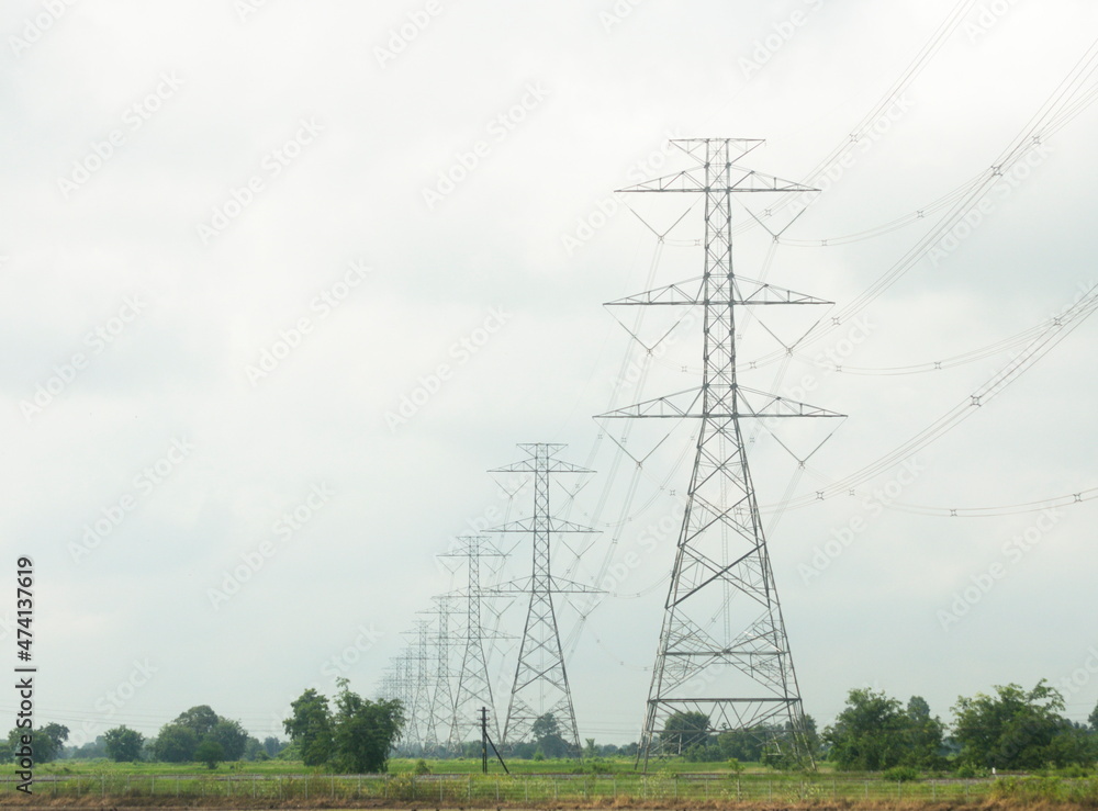 Poles and high voltage transmission lines on sky and clouds background
