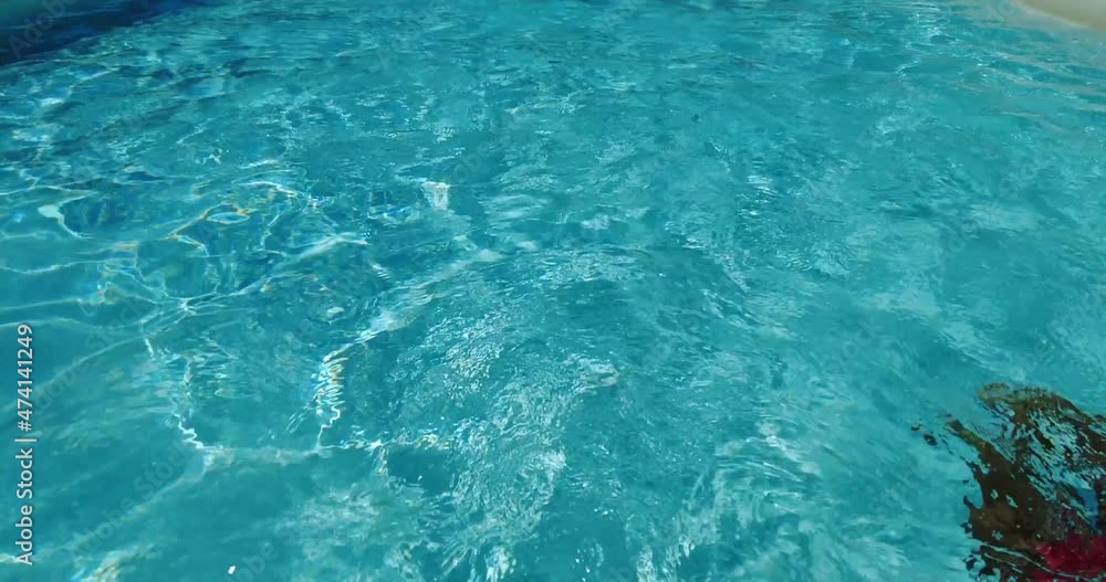 African American child swims in the turquoise water of the pool. A warm summer day. African American child swims in the turquoise water of the pool. A warm summer day.