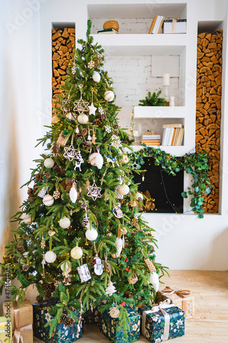 Fototapeta Naklejka Na Ścianę i Meble -  a large Christmas tree with boxes of gifts by the decorative fireplace