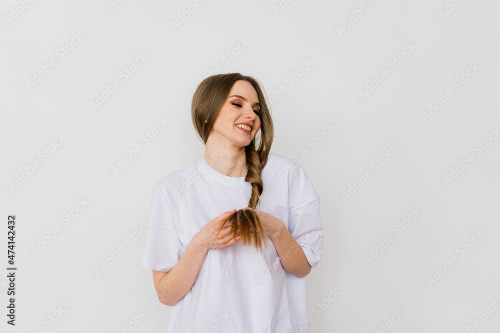 Girl touching her hair and smiling while posing at interior looking in the mirror Girl touching her hair and smiling while posing at interior looking in the mirror