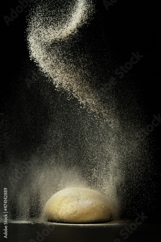 flour sprinkled on dough on a black background.