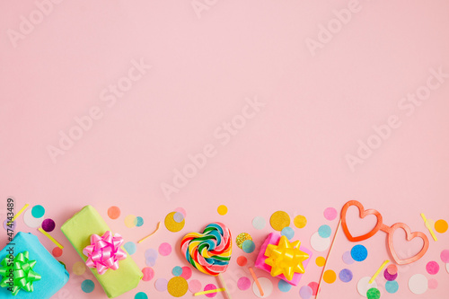 Heart shaped lollypop and decorative paper eye glasses, gift boxes on pink background with confetti © lithiumphoto