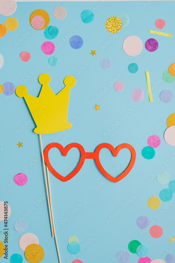 Paper heart shaped eye glasses with multicolored confetti on blue background