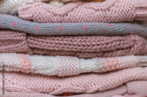 A stack of knitted baby hats and snoods in beige and pink shades