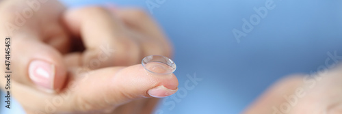 Woman holds contact lens and storage container on finger closeup