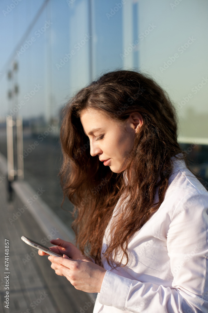 Beautiful young woman with mobile phone using technology for texting or social media in the city