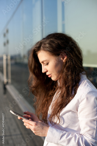 Beautiful young woman with mobile phone using technology for texting or social media in the city