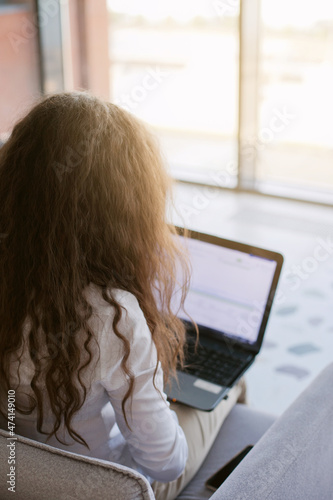 Young woman working on laptop in the public pplace. Caucasian woman with brown hair in the office and using laptop. Laptop screen photo