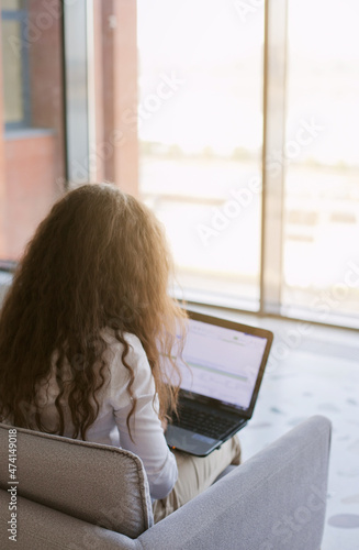 Young woman working on laptop in the public pplace. Caucasian woman with brown hair in the office and using laptop. Laptop screen