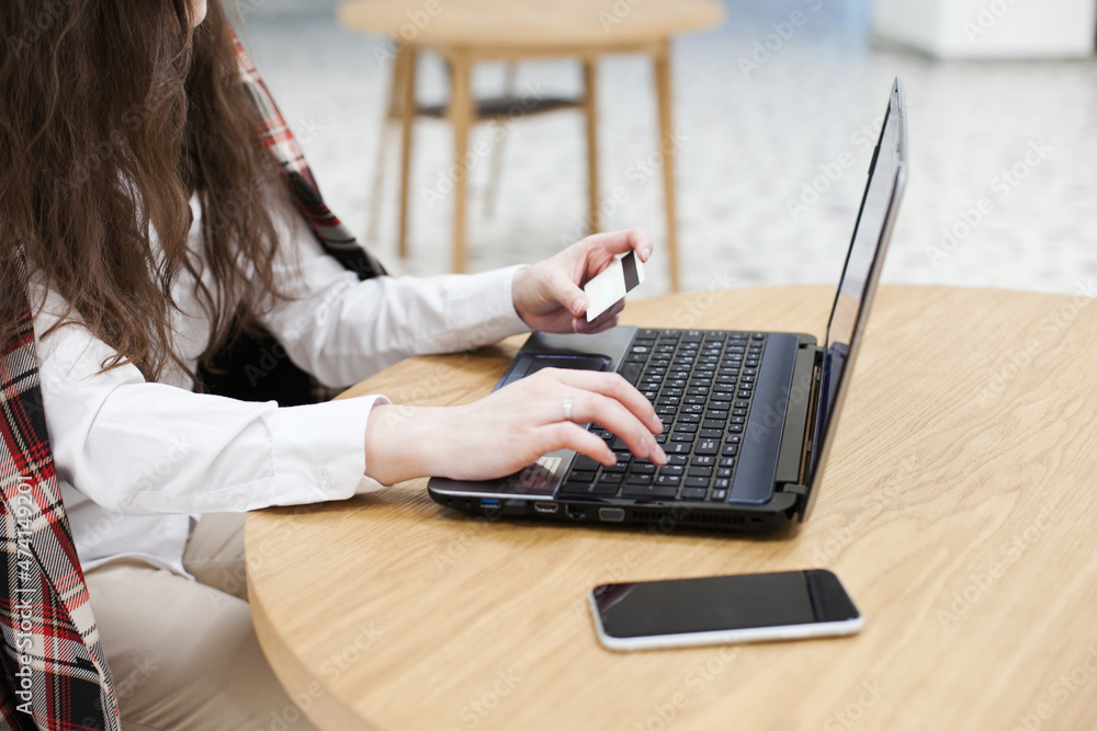 Fototapeta premium woman working on laptop and using credit card at the office or cafe. Caucasian woman with brown hair internet shopping at cafe