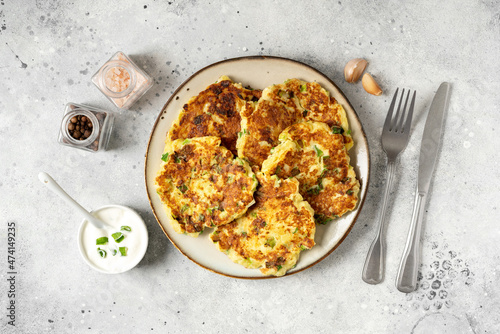 Homemade potato pancakes with cottage cheese and green onions in a ceramic plate on a bright kitchen table close-up. A traditional dish of European cuisine made of vegetables	