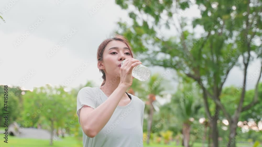 Asian woman take a break, drinking water from bottle after exercise. Asian woman take a break, drinking water from bottle after exercise.