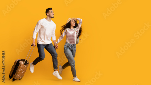 Travel Ad. Excited Young Middle Eastern Couple Running With Suitcase
