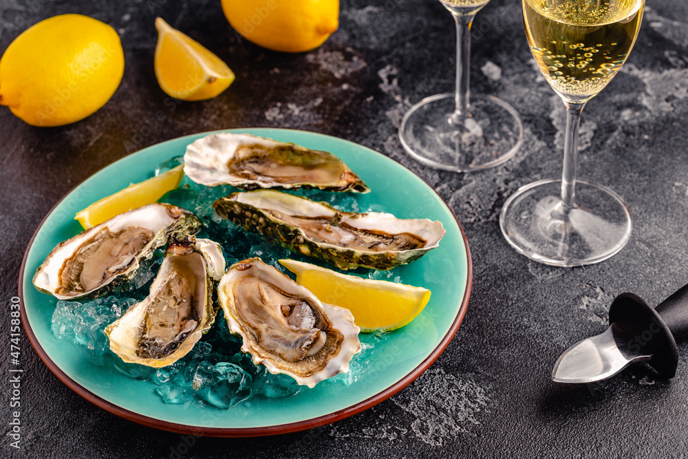 Opened fresh oysters on a blue plate, served with lemon and ice.