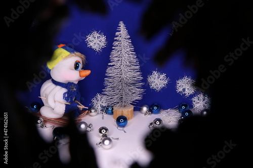 Christmas composition.Snowman toy,silver small tree,glass balls,snowflakes for decor .Peeping look 