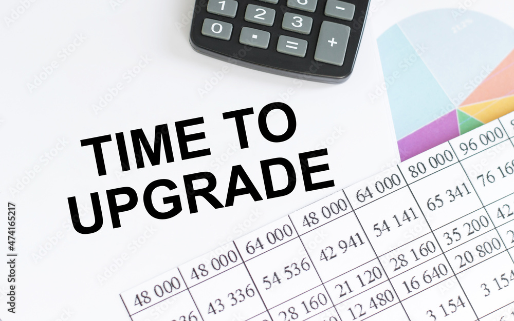 Text TIME TO UPGRADE on notepad next to reports, charts and calculator on your office desk, business concept Text TIME TO UPGRADE on notepad next to reports, charts and calculator on your office desk, business concept