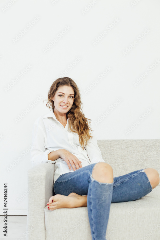 a beautiful woman sitting on the couch in home clothes