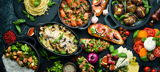 Food: cheese, figs, mushrooms, meat and vegetables. European and Asian cuisine. Healthy food on a black stone background. Top view.