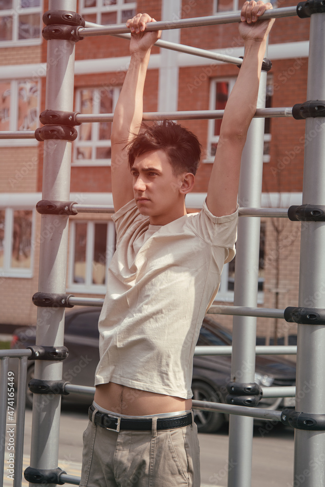 Portrait of a young guy doing sports on the horizontal bar. Outdoor playground for athletes. Portrait of a young guy doing sports on the horizontal bar. Outdoor playground for athletes.