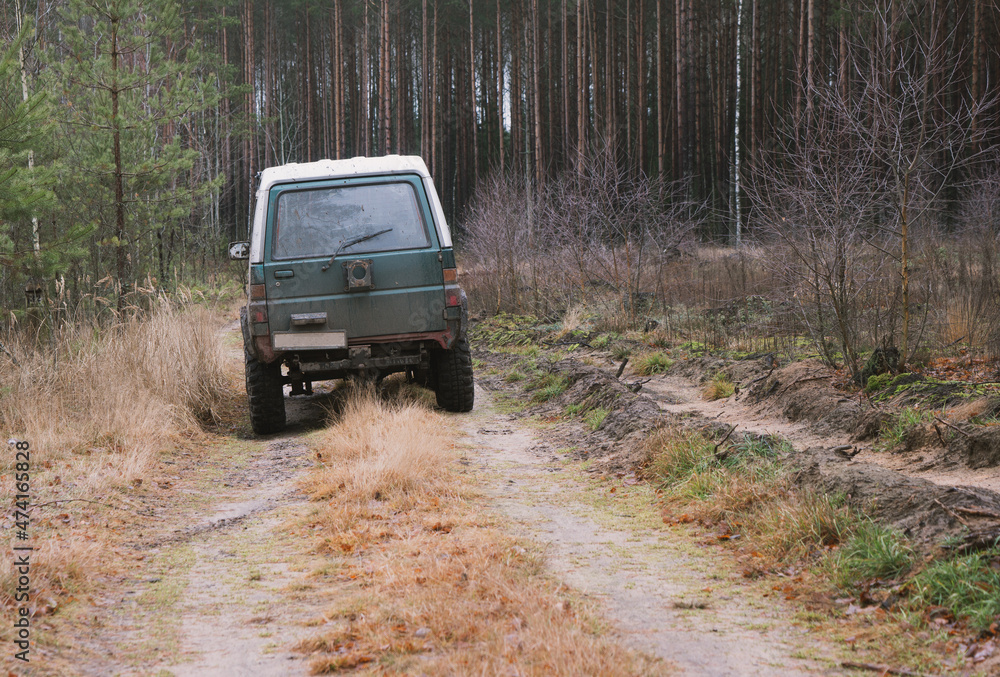 Photo of an off-road black car on muddy gravel road. Rally racing SUV in the forest