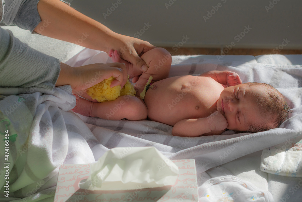 madre limpia a su bebe recién nacido con una esponja de ducha Stock Photo