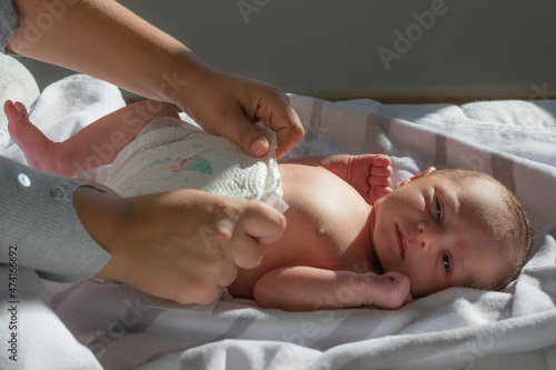 las manos de la madre poniendo el pañal a su hijo recién nacido photo