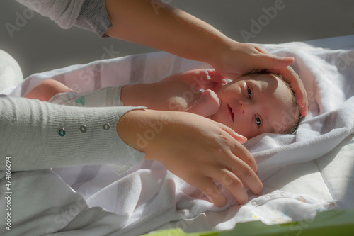 recién nacido mirando a cámara mientras su madre le acaricia después de la ducha photo