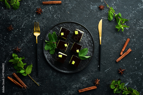 Chocolate mousse dessert Opera on a black plate with mint. Top view. Rustic style.