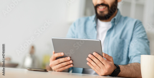 Young man using digital tablet, browsing internet or reading news, enjoying weekend and resting at home