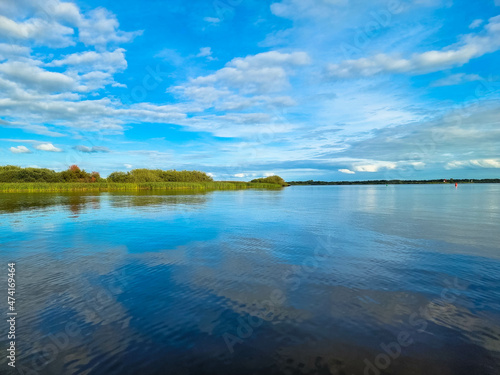 View over the wetland in natural park and protected area with green reed, water and blue sky. Burgumer Meer near Leeuwarden, Friesland, The Netherlands