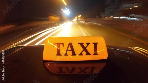 Intercity cab service concept, nightlapse footage of Taxi sign mounted on vehicle rooftop driving photo