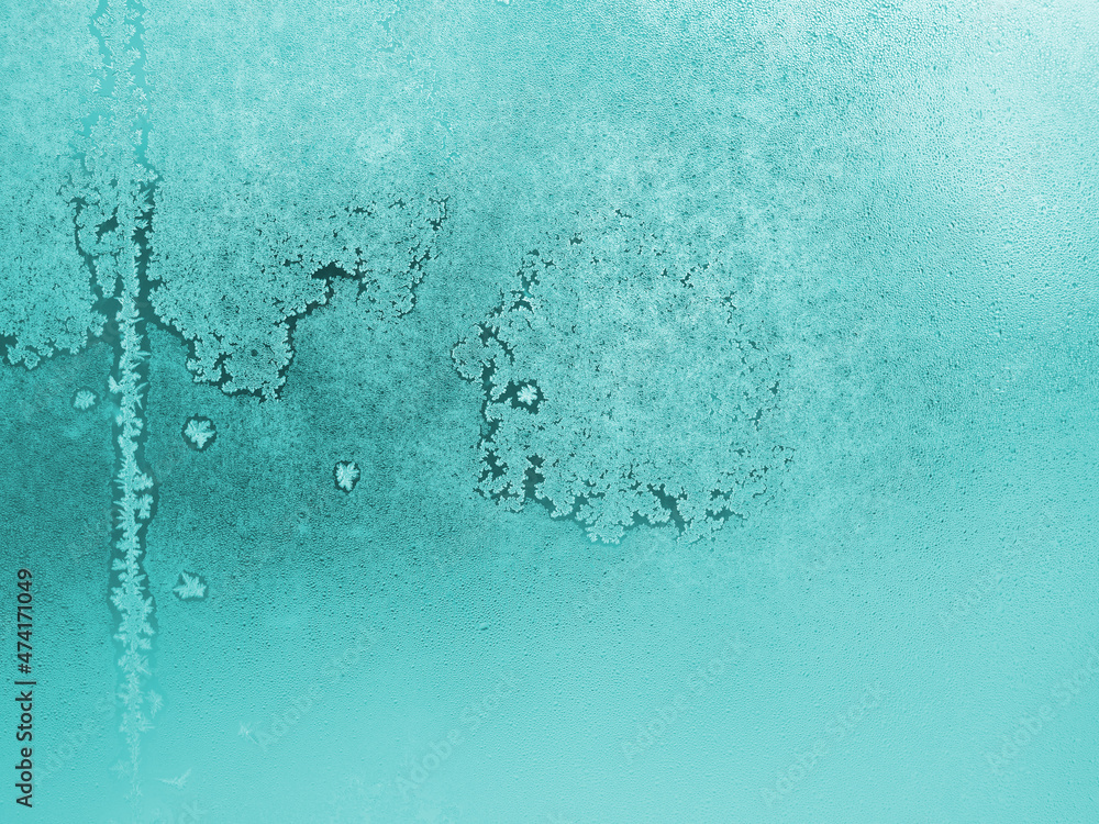 Frozen and misted window glass. Abstract winter aquamarine background. Ice crystals and water droplets. Light turquoise wallpaper. Tinted natural backdrop. Misty or translucent surface