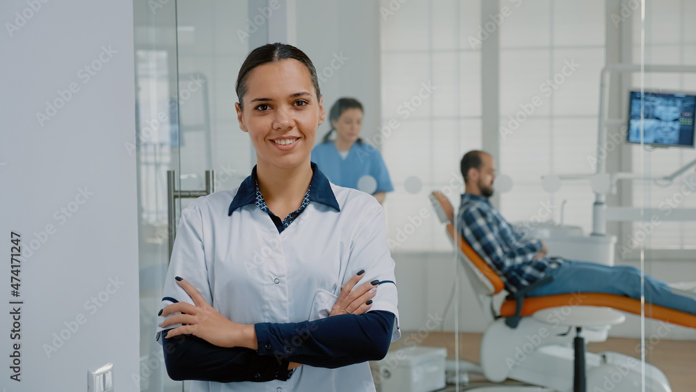 Obraz premium Portrait of woman with stomatologist occupation standing in oral care cabinet and smiling. Caucasian dentist with professional expertise looking at camera prepared for patient consultation