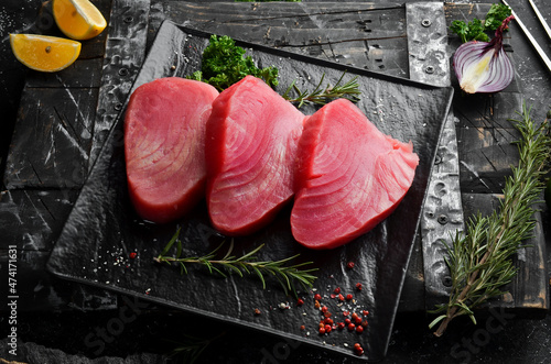 Fresh juicy tuna steak on a black stone plate. On a dark background. Top view. photo
