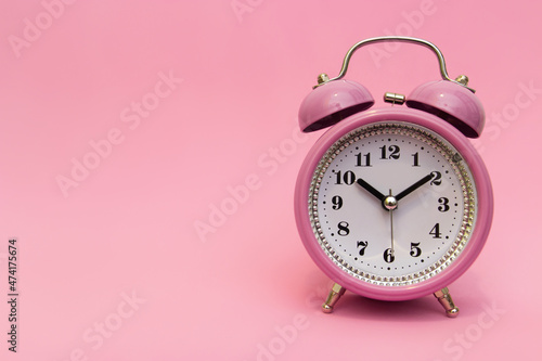 Old pink baby alarm clock rings loudly. A lot of work ahead, to learn all the lessons. Time to wake up and get work done. Isolated object, place for signature or advertisement on a pink background.