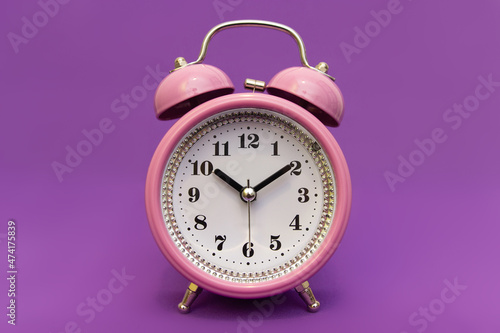 Alarm clock on an isolated minimalistic background in color 17-3938 very peri. Time to look for gifts for loved ones, time to celebrate. The holiday is coming soon. Meet the deadline.