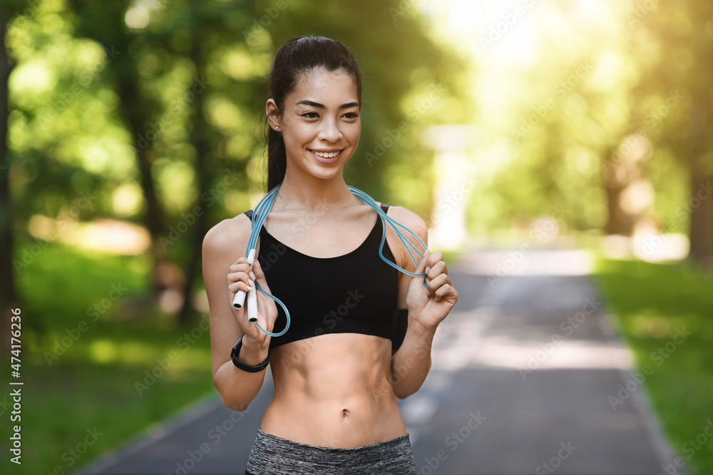Fototapeta premium Pretty Athletic Asian Girl Exercising With Skipping Rope In Park, Training Outdoors