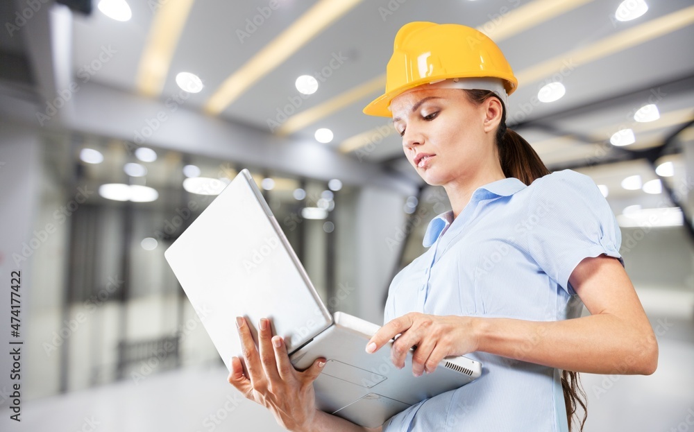 Young woman architect wearing hardhat at construction site while working. Young woman architect wearing hardhat at construction site while working.
