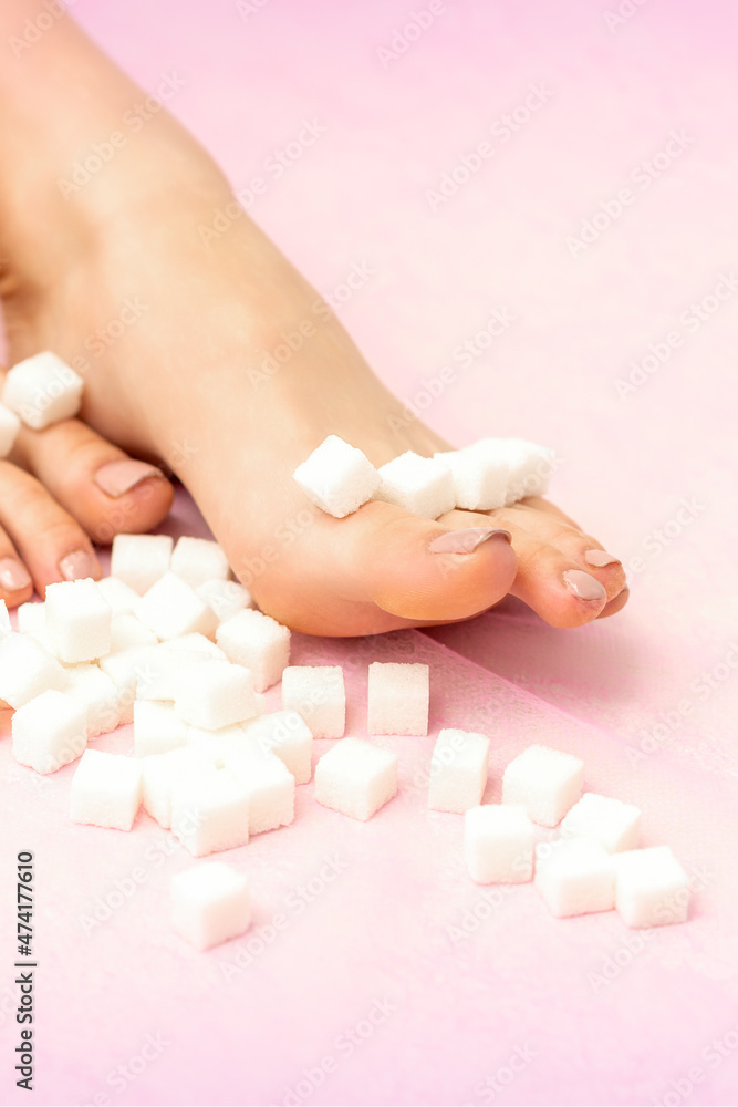 Sugar cubes lying in a row on female feet on pink background with copy space, depilation concept Sugar cubes lying in a row on female feet on pink background with copy space, depilation concept